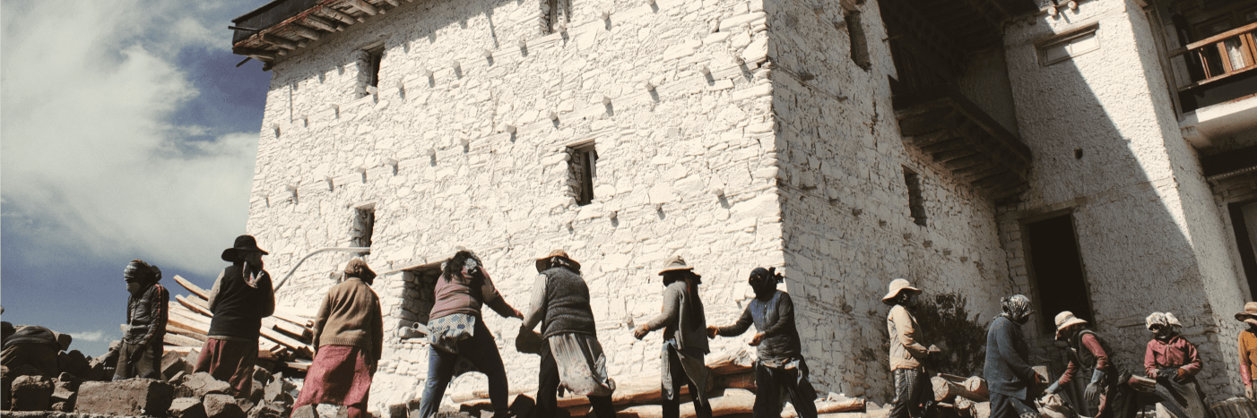 Artisans and locals walking past a traditional Himalayan building